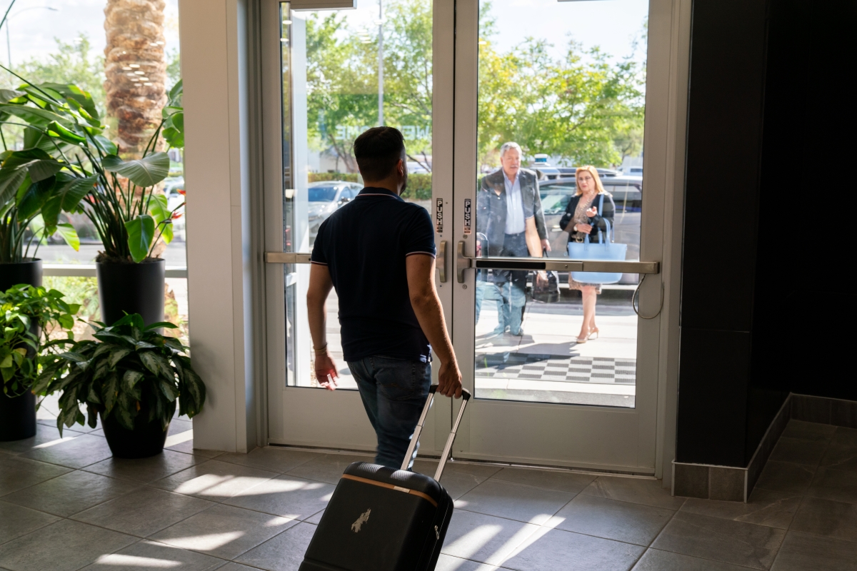 A man rolls his suitcase toward a waiting robotaxi