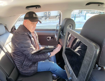 A Motional vehicle operator sits in the backseat of an IONIQ 5 robotaxi working on a tablet