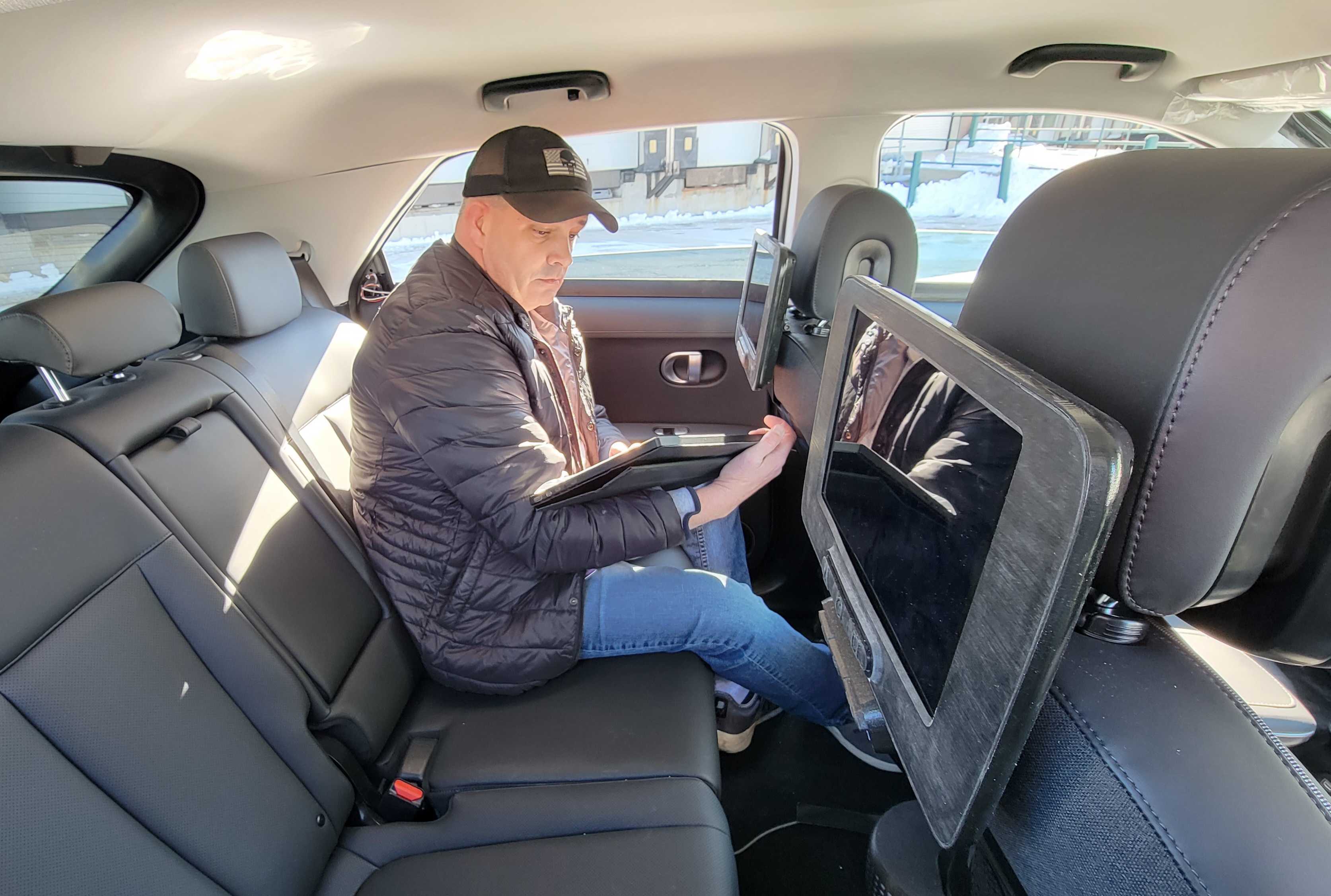 A Motional employee takes notes on a tablet while sitting in the backseat of an IONIQ 5 robotaxi 