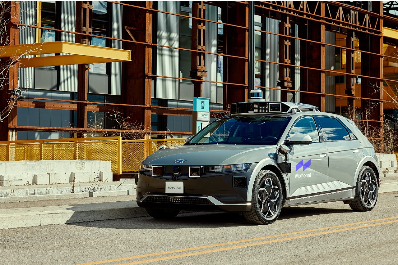 A gray IONIQ 5 robotaxi is parked in front of Hazlewood Green, a renovated steel mill in Pittsburgh. 