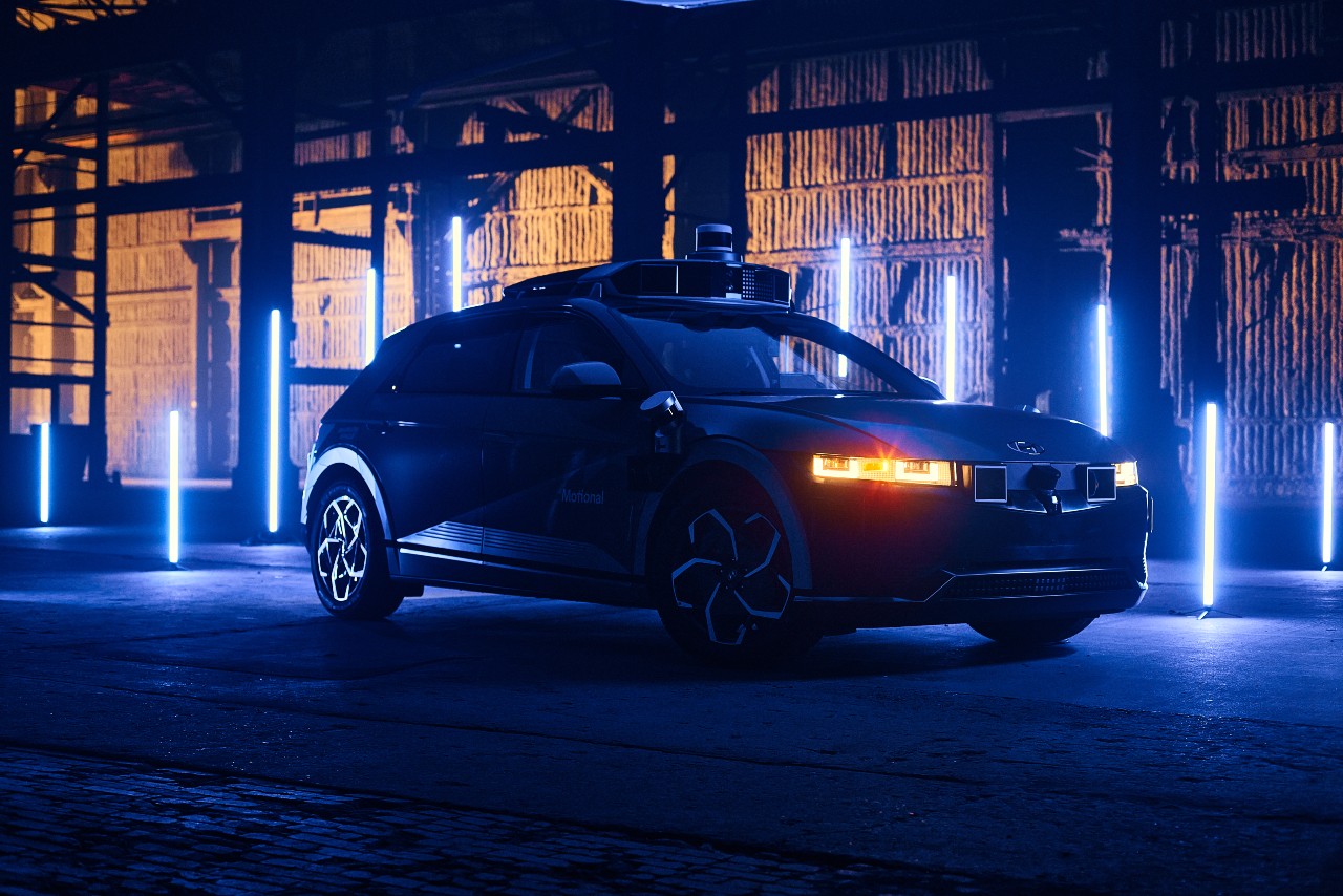 The Motional IONIQ 5 robotaxi is seen on a dim soundstage with blue LED lights in the background
