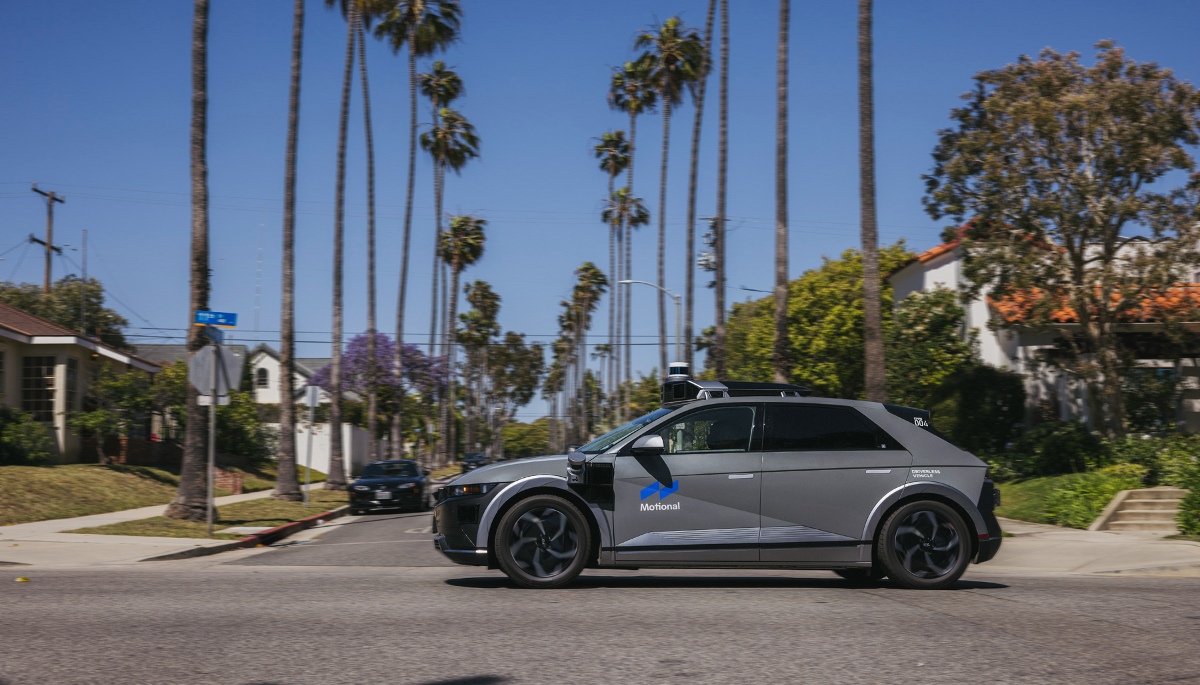 A gray IONIQ 5 robotaxi drives in past a Santa Monica street that's lined with palm trees