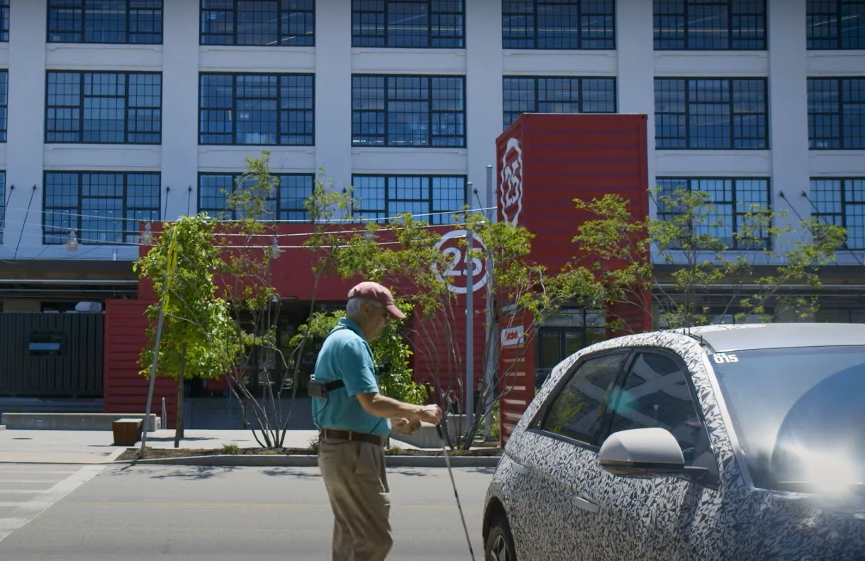 A blind man walks to an awaiting Motional IONIQ 5 robotaxi outside the Boston Design Center