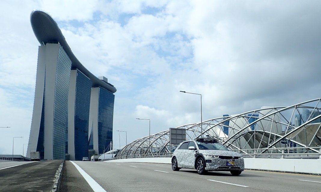 The IONIQ 5 robotaxi drives in Singapore with the iconic Marina Sands hotel in the background