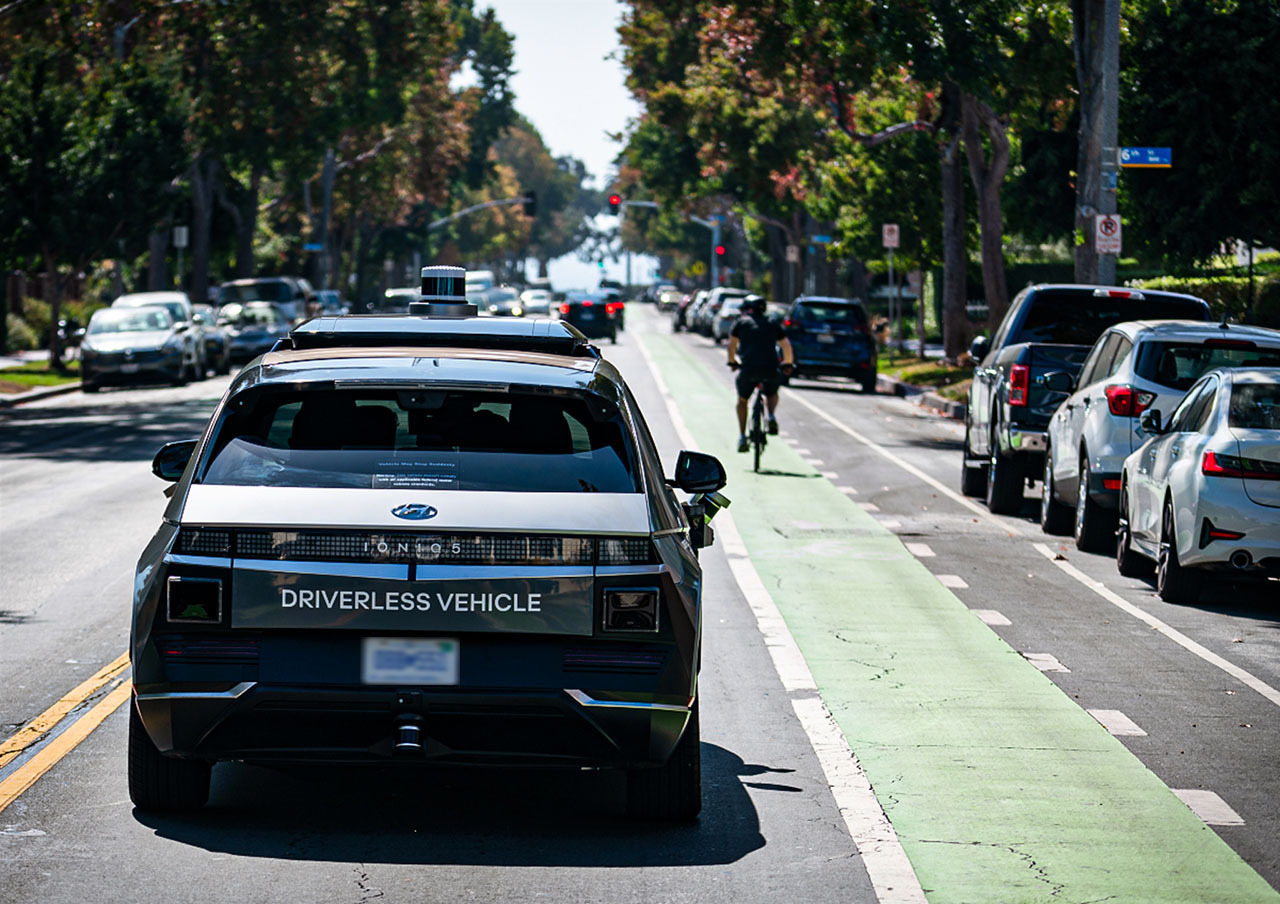 An IONIQ 5 robotaxi safely shares a Los Angeles street with a cyclist in a marked bike lane