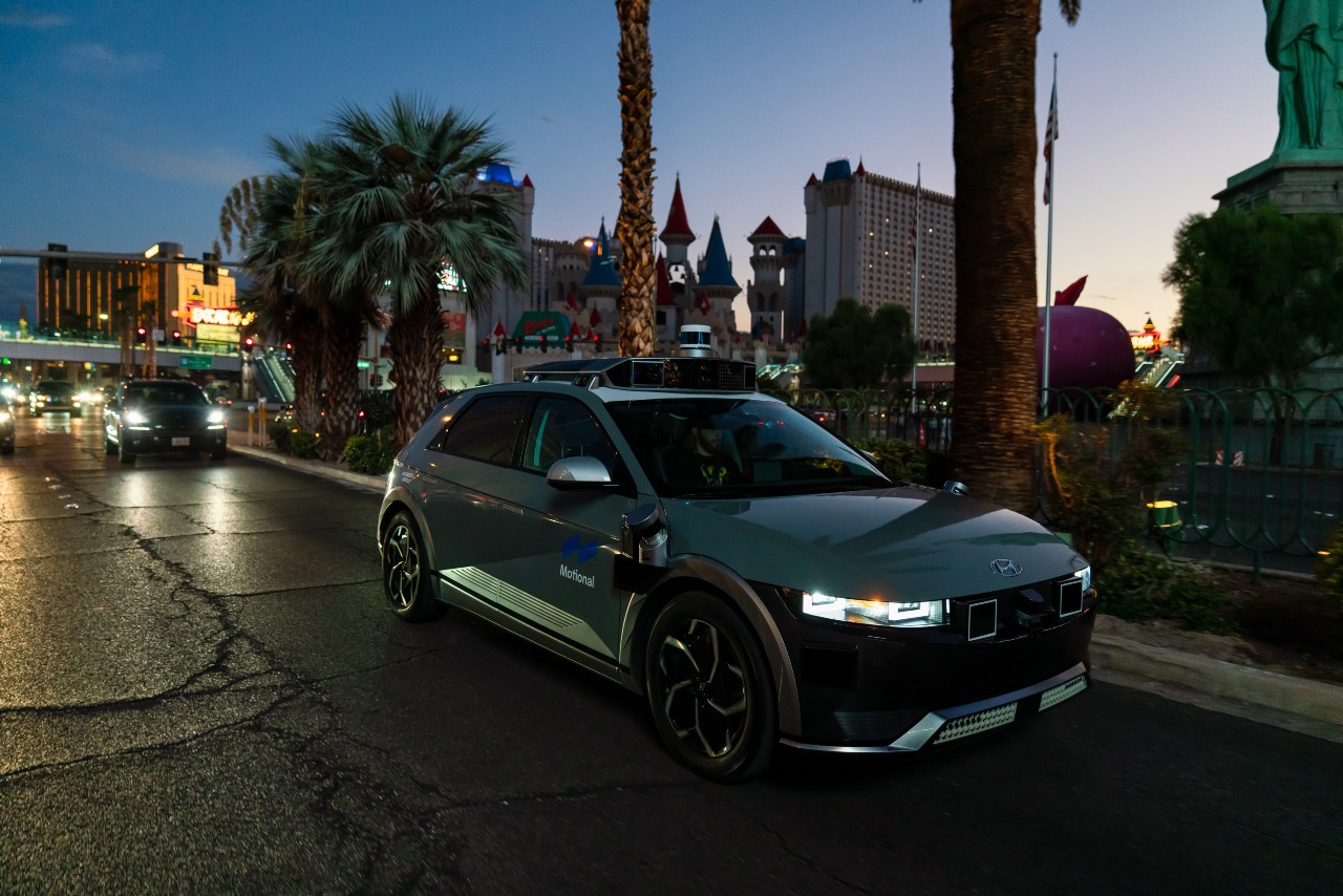 A silver Motional IONIQ 5 robotaxi drives down the Las Vegas Strip at dusk