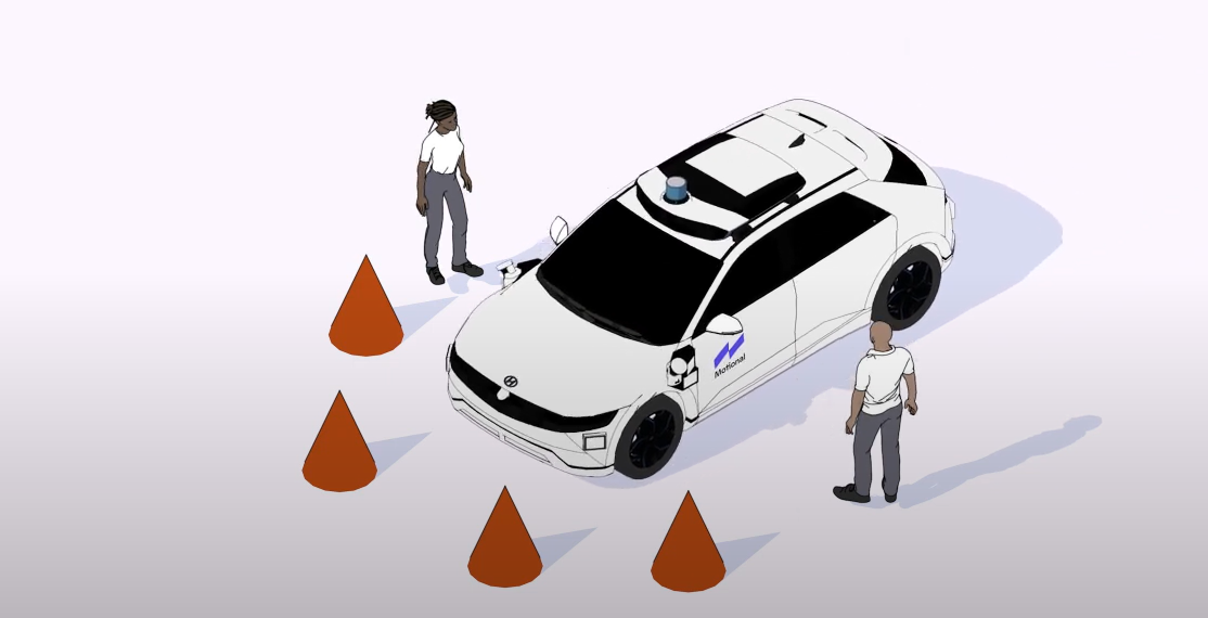 A graphic showing a Motional IONIQ 5 robotaxi stopped at four orange cones with two people inspecting it