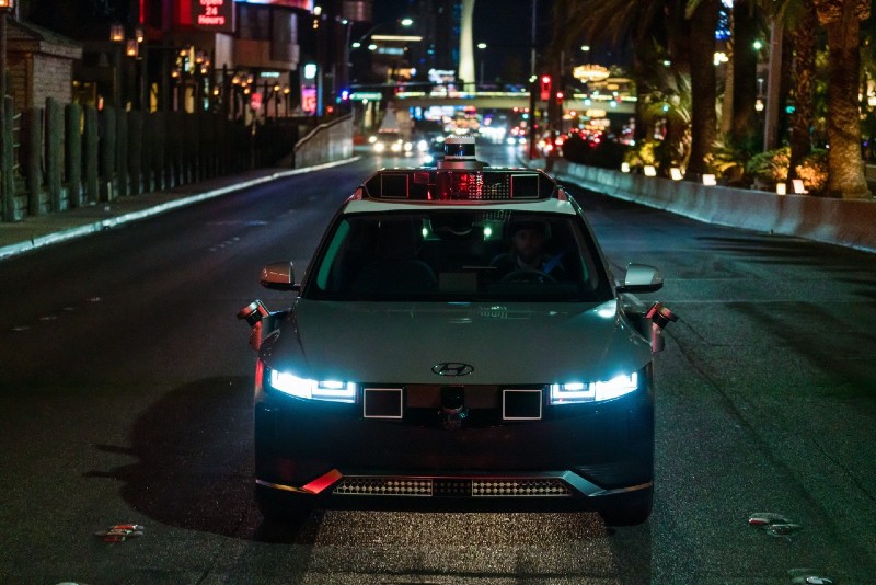 A silver Motional robotaxi drives on the Las Vegas Strip at night