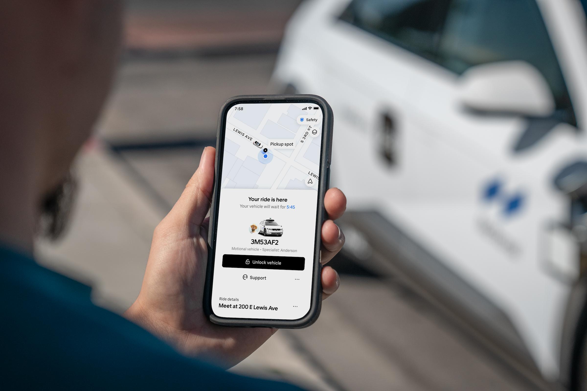 A hand holding a phone with an Uber "Your Ride is Here" notification for a Motional robotaxi
